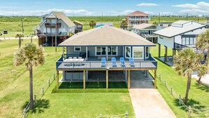 Una casa frente a la playa con balcón, terraza cubierta y patio cercado.