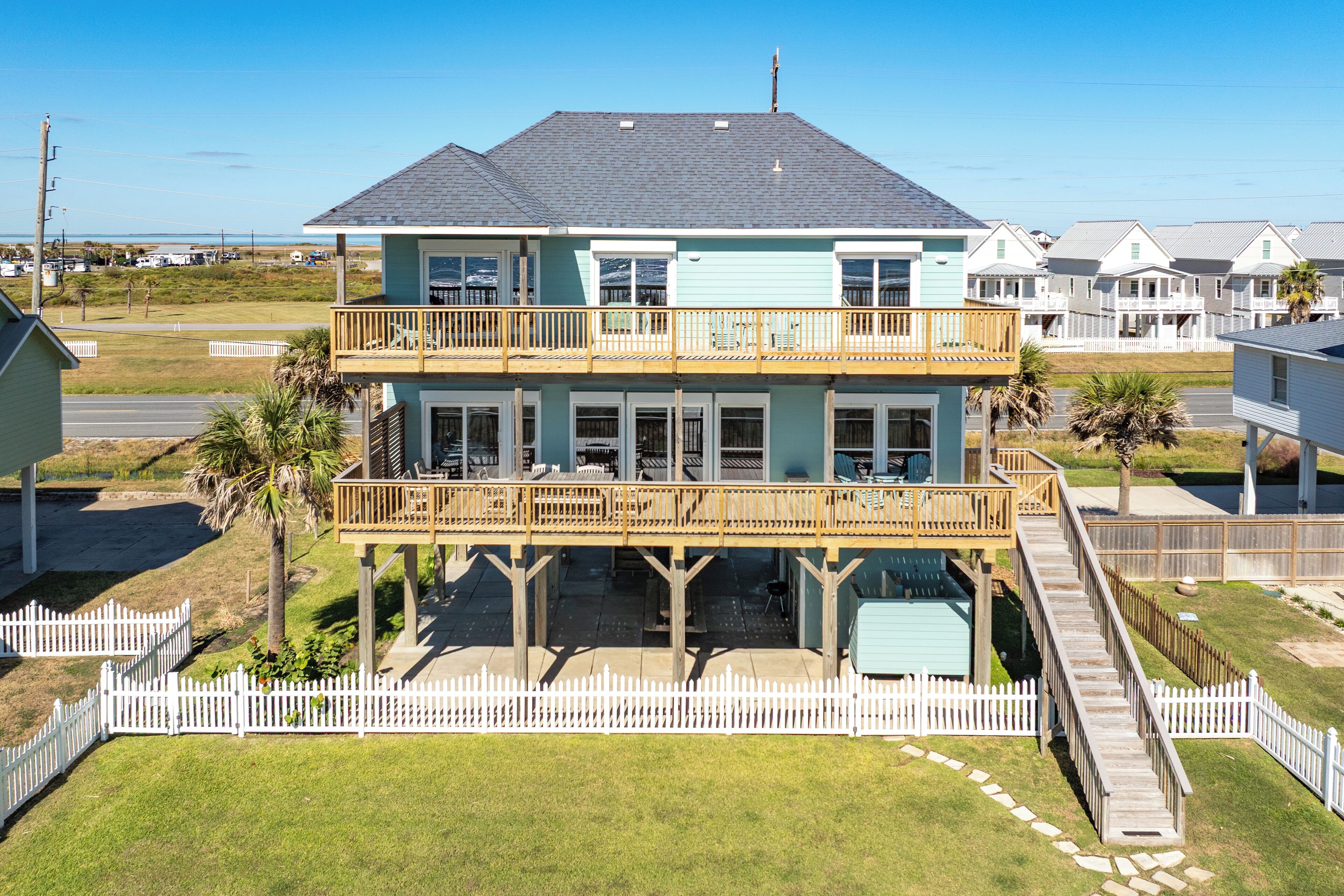 Una casa frente al mar de dos pisos, con balcón y un espacio al aire libre cubierto.