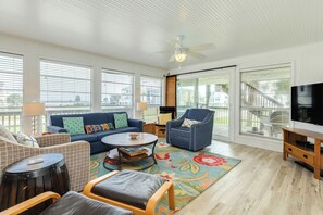 A spacious living room with a sofa, armchairs, a coffee table, and a TV.