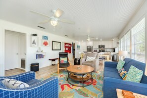 A spacious living room with a blue sofa, a round coffee table, and a ceiling fan.