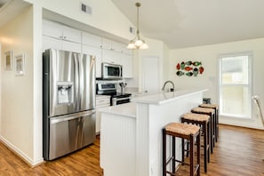 A modern kitchen with stainless steel appliances, white cabinetry, and a central island with bar stools.