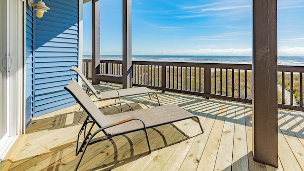A wooden deck with two lounge chairs, a railing, and a view of the ocean. - Updated Beachfront Home w/ Elevator+Ramp, 2 Primary Suites, Great Gulf Views (Galveston)
