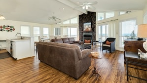 A spacious living area with a large brown sectional sofa, a dining table, and a kitchen area with a white countertop and cabinets. - Updated Beachfront Home w/ Elevator+Ramp, 2 Primary Suites, Great Gulf Views (Galveston)