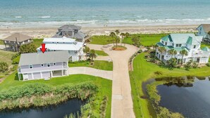 A coastal property with a large house, a pond, and a beach view. - Bright & Airy 3rd Row Home w/ Gulf Views, 2 Decks, Outdoor Shower, Free Wifi (Galveston)
