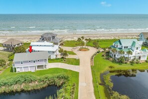 A coastal property with a large house, a pond, and a beach view.