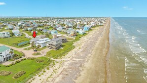 An aerial view of a coastal residential area with houses, a beach, and a clear sky. - Bright & Airy 3rd Row Home w/ Gulf Views, 2 Decks, Outdoor Shower, Free Wifi (Galveston)