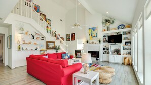 Un salón amplio con un sofá rojo, una escalera blanca y una chimenea.