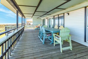 A wooden deck with a covered seating area, a table, and chairs. - Updated Beachfront Home w/ Gulf Views, 2 Decks, Free Wifi, Open Layout (Galveston)