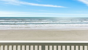 Uitzicht op een strand met een witte balustrade op de voorgrond.