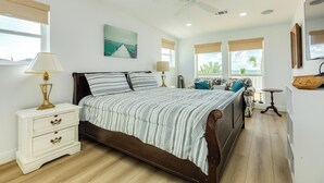 Ein Schlafzimmer mit einem Bett, Nachttischen, einem Deckenventilator und Blick ins Freie.