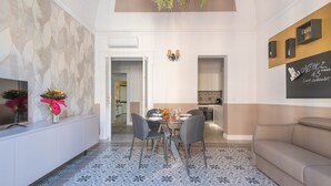 A dining area with a table set for four, a sofa, and a TV on the left.