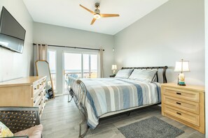 A bedroom with a bed, bedside tables, a dresser, a ceiling fan, and a TV mounted on the wall. - Elevator, 2 Decks, Gulf Views all Bedrooms & More - Private Beachfront Home (Galveston)