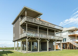 A multi-story building with a covered porch, a staircase, and a view of the surrounding area. - Elevator, 2 Decks, Gulf Views all Bedrooms & More - Private Beachfront Home (Galveston)
