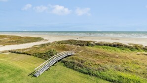 A coastal landscape with a wooden boardwalk leading to a sandy beach. - Elevator, 2 Decks, Gulf Views all Bedrooms & More - Private Beachfront Home (Galveston)