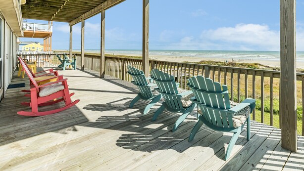 A wooden deck with rocking chairs and Adirondack chairs overlooking a beach. - Elevator, 2 Decks, Gulf Views all Bedrooms & More - Private Beachfront Home (Galveston)