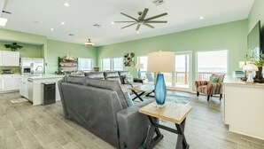 A spacious living area with a gray sofa, a wooden coffee table, and a ceiling fan. - Elevator, 2 Decks, Gulf Views all Bedrooms & More - Private Beachfront Home (Galveston)