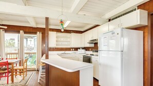 Una cocina con armarios blancos, un refrigerador blanco e isla de madera.