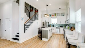 Una cocina moderna con una isla central, suelo de madera y armarios blancos.