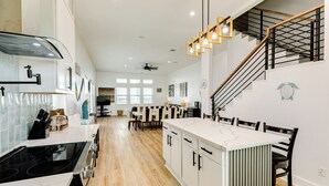 Una cocina moderna con una isla central, suelo de madera y una escalera que sube a un nivel superior.