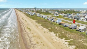 Vista aérea de una zona residencial costera con casas, una playa y una carretera.