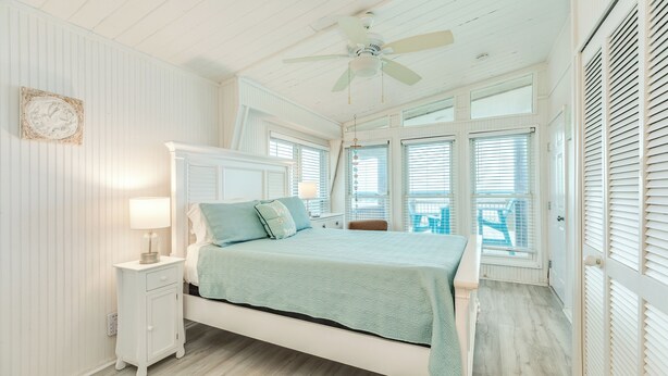 Ein Schlafzimmer mit Bett, Nachttisch und Deckenventilator.