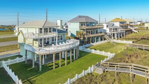 Una casa costera con balcón, terraza de madera y valla de piquete blanca.