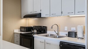 A modern kitchen with white cabinets, a black stove, a microwave, and a dishwasher. - Kalani Kai#104 1st Floor, Remodeled Unit in Heart of Kona Town! Best location (Kailua Kona)
