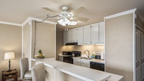 A kitchen with a white countertop, a ceiling fan, and a bar stool. - Kalani Kai#104 1st Floor, Remodeled Unit in Heart of Kona Town! Best location (Kailua Kona)