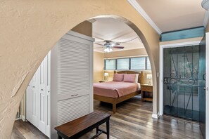 Une chambre à coucher comprenant un lit, un banc, un ventilateur de plafond et une porte-fenêtre coulissante.