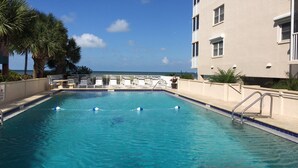 Ein Swimmingpool mit Liegestühlen und Blick auf den Ozean.
