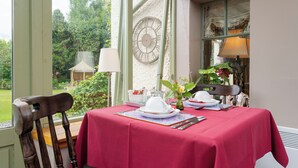 A dining table set with white plates, a red tablecloth, and a clock on the wall. - The Firs (Pitlochry)