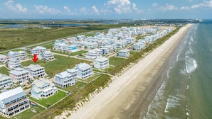 An aerial view of a coastal residential area with beachfront properties, a sandy beach, and a clear view of the ocean. - 2nd Row Dog Friendly Home w/ Gulf views, 2 Decks, Screened Area (Galveston)