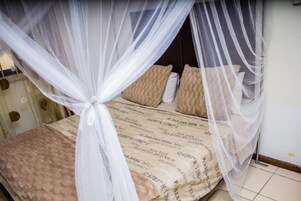 Una cama con dosel, ropa de cama estampada y almohadas.