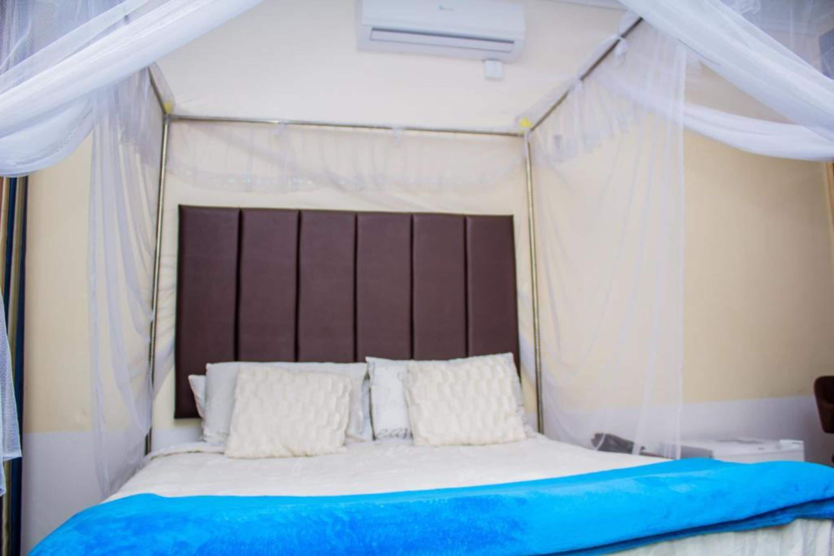 A bedroom with a bed, white curtains, and a ceiling fan.