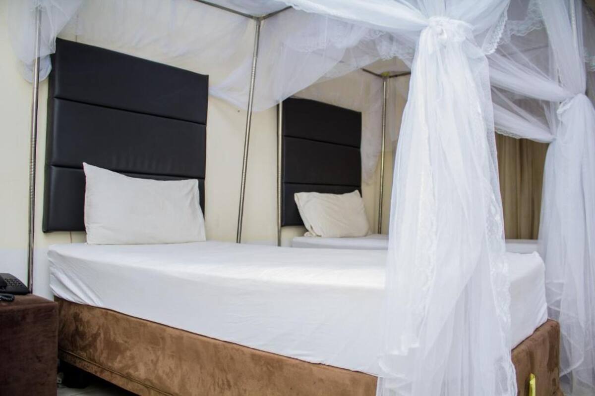 A room with a bed, a bedside table, and a canopy bed.