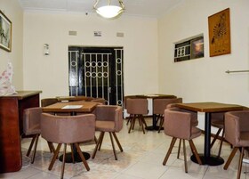 Un comedor con mesas, sillas, una barra y una puerta con reja de metal.