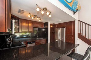 Une cuisine moderne avec des meubles en bois foncé, des appareils électroménagers en acier inoxydable et un îlot central.