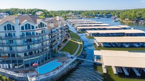 A waterfront hotel with multiple balconies, a swimming pool, and docked boats.