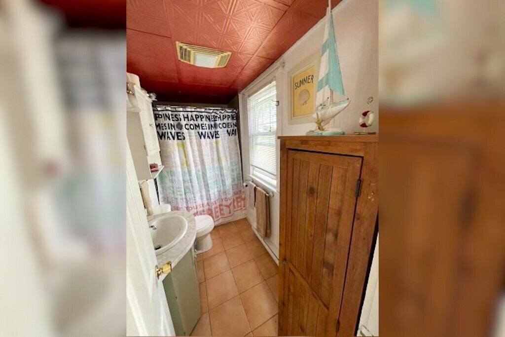 A bathroom with a toilet, sink, and wooden cabinet.