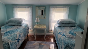 Een kamer met twee bedden, een klein tafeltje, een lamp en een decoratie aan de muur.
