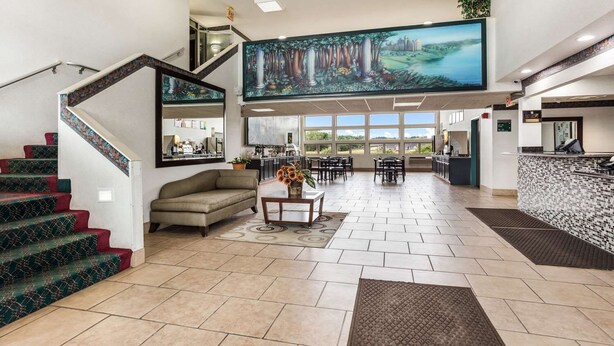 A spacious lobby with a staircase, a sofa, a coffee table, and a large painting. - Quality Inn Clare (Clare)