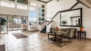 A hotel lobby with a reception desk, a sofa, a staircase, and a large window. - Quality Inn Clare (Clare)