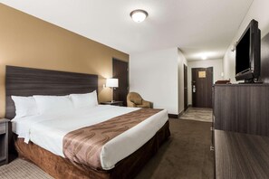 Ein Hotelzimmer mit einem großen Bett, einem Fernseher, einem Sessel und einem Schreibtisch.