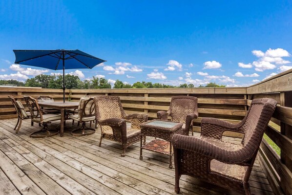 A wooden deck with wicker furniture, including a table and chairs, under a blue umbrella. - Quality Inn Clare (Clare)