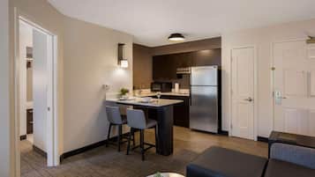 A modern kitchen with a central island, bar stools, and a refrigerator.