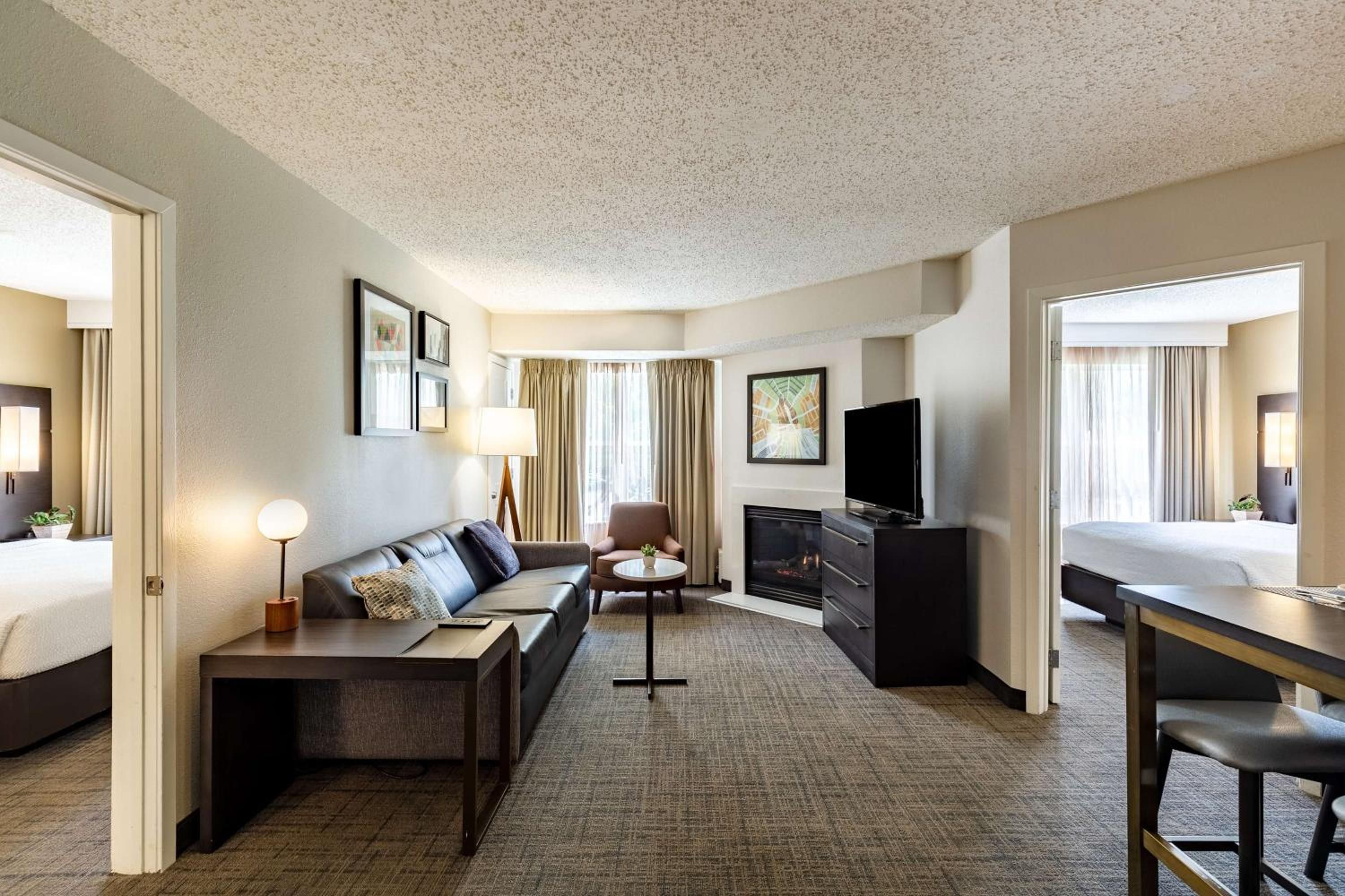 A hotel room with a sofa, a desk, a TV, a fireplace, and a bed.