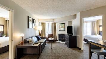 A hotel room with a sofa, a desk, a TV, a fireplace, and a bed.