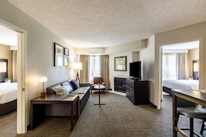 Une chambre d’hôtel avec un canapé, un bureau, une télévision, une cheminée et un lit.