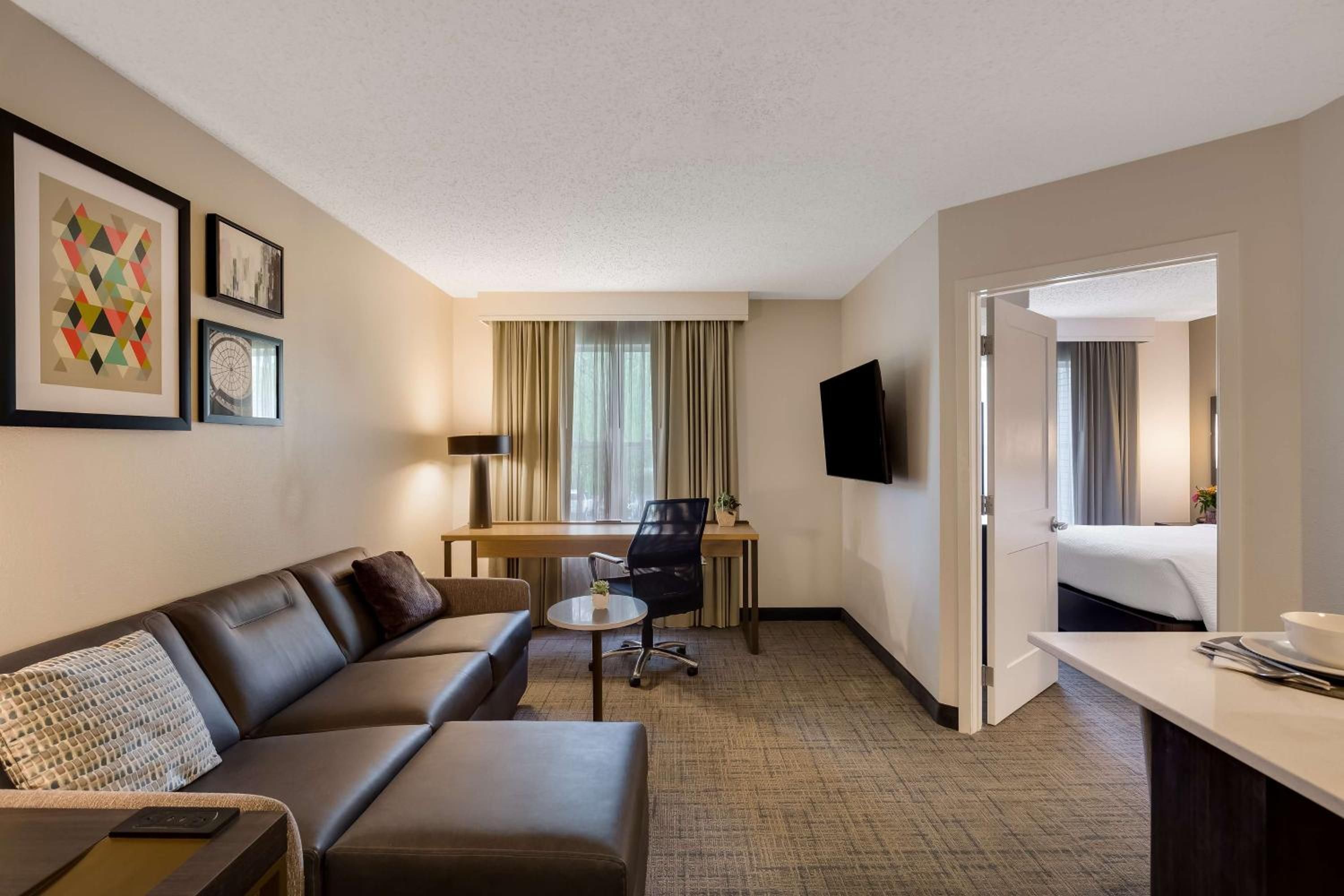 Habitación de hotel con sofá, escritorio, silla, televisor y cama.