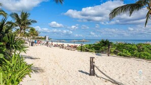 Ein Strand mit weißem Sand, Palmen und Sonnenschirmen.